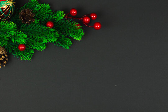Festive christmas composition fir branches with red berries on a plain black background, copy space