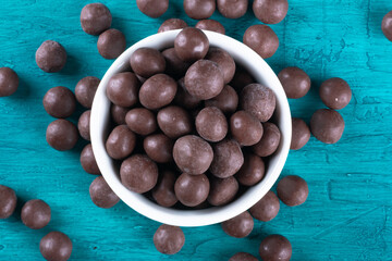 Chocolate balls in white bowl on blue background.