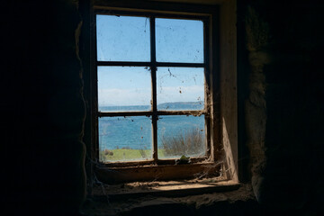 View to blue sky and sea through dirty old multi-paned widow