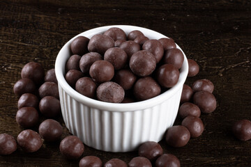 Chocolate balls in white bowl on rustic background.