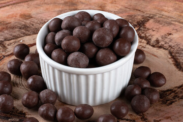 Chocolate balls in white bowl on wooden background.