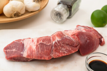 Fresh raw pork meat and some ingredients for marinade close up on a marble board on white background