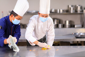 The male chef cleaning the kitchen with his helper