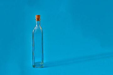 Botella vacía de cristal con pergamino y originales formas sobre fondo solido neutro de color. Iluminación de estudio. Concepto para publicidad con espacio de letrero o edición.