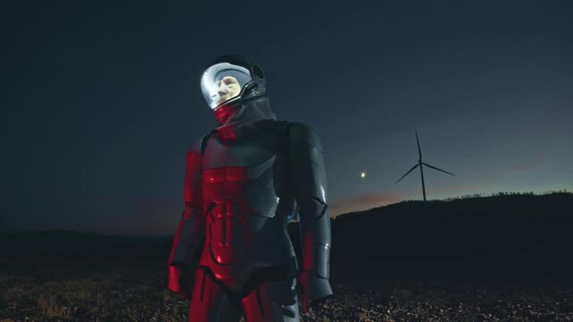 Space man. Night view at the man astronaut walking on the empty field and admiring the beautiful earth with windmills at the background. Man looking at the sides. Futuristic, galaxy, interstellar