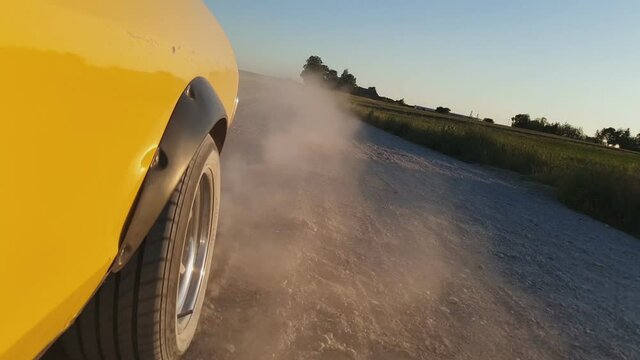 Yellow Vintage Car Drives on a Dusty Rural Gravel Road