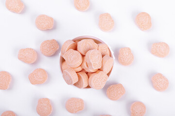 Top view of animal drawings on pink ecstasy pills in a lid isolated on white background