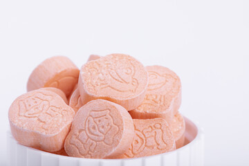 Closeup shot of animal drawings on pink ecstasy pills in a lid isolated on white bckground