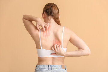 Young allergic woman scratching her skin against color background