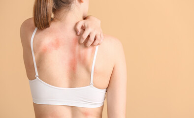 Young allergic woman scratching her skin against color background