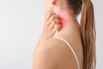 Young allergic woman scratching her skin against light background