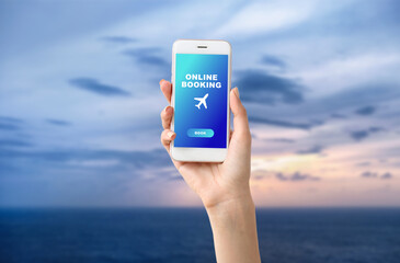 Hand of woman with mobile phone at sea resort. Concept of online booking
