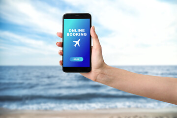 Hand of woman with mobile phone at sea resort. Concept of online booking