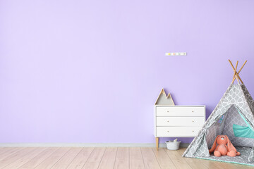 Chest of drawers and childish wigwam near color wall