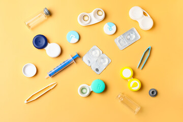 Containers with contact lenses, solution, tweezers and syringe on color background