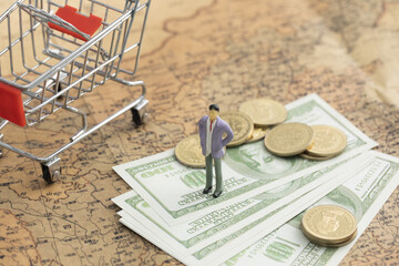 Selective focus closeup of a toy male, toy cart, coins, and dollar paper bills