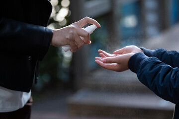 息子の手に消毒液をスプレーする母親
