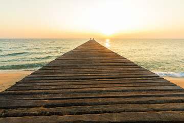 Wooden bridge on sea for entry to the beautiful ocean at sunset.
