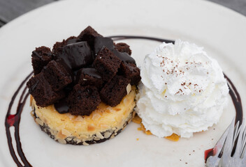 Close of brownie cheesecake with whip cream in the white disk