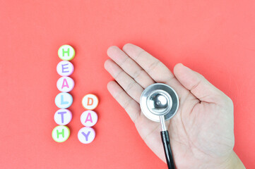 Fototapeta na wymiar Top view of man hand, stethoscope and alphabet erasers with text HEALTH DAY. 