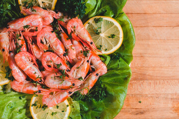 prepared shrimp with lemon and lettuce served on a wooden board