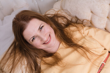 Naklejka premium Attractive midle aged woman laying on sofa and looking up into the camera