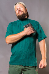 Joyful bearded craftsman in green t-shirt having fun with staple gun