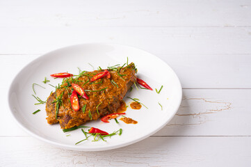 Close up view of Spicy Red Curry with crispy fried fish,  on white dish