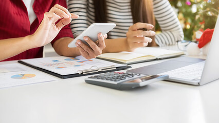 Business team are discussing financial data and report graph on last working day. Young creative people are celebrating holiday in modern office. Merry Christmas and Happy New Year.