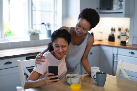 Mixed race female couple taking a selfie during breakfast in kichen