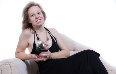 Cheerful 40 years old woman in black dress having relax on sofa with glass of wine