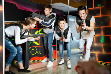 Fototapeta premium Fine people aiming laser guns at other players during lasertag game in dark room
