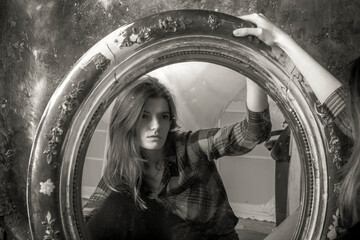 Young longhaired beautiful woman sitting in front of the vintage mirror