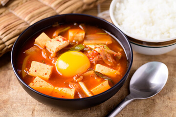 Korean food, Kimchi soup with tofu and egg eating with cooked rice on wooden background