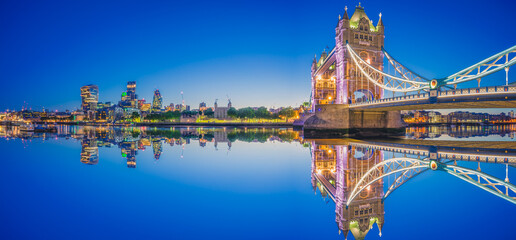 Panorama of Tower Bridge and illuminated skyscrapers in financial district in London, UK