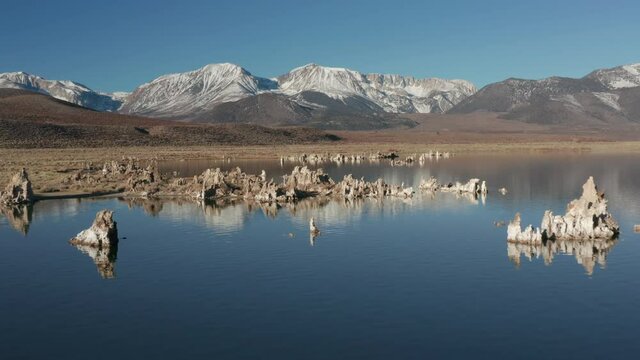Drone flying straight over Mono Lake toward snowy mountains on winter morning