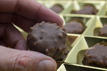 Closeup of chocolate in hand  on golden box presentation background