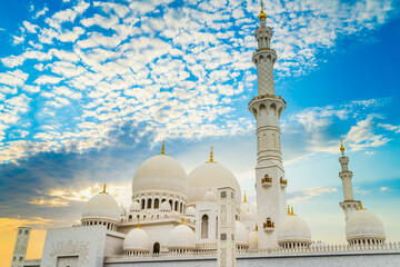 Fototapeta na wymiar Domes of Grand Mosque in Abu Dhabi with sunset sky