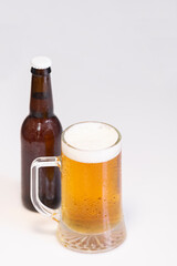 Select focus of a tempting cold mug of beer with an out of focus beer bottle at the back