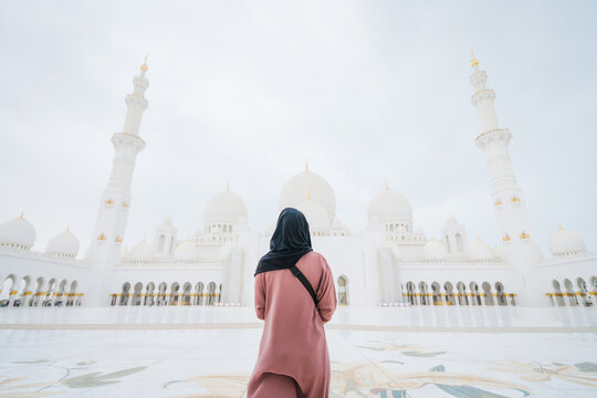Woman wearing black hood in front of mosque in Abu Dhabi - selective focus 