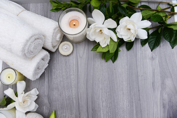 Spa composition with white gardenia andcandle,, and herbal ball and three rolled towel  on wooden...