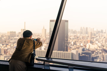 Tourist taking photo of city from the observation deck of Tokyo tower 