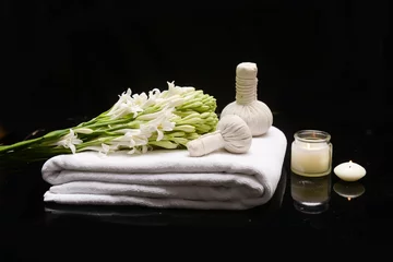 Keuken spatwand met foto spa concept with bunch of tuberose flowers ,buds with herbal, ball on towel, ,candle on black background   © Mee Ting