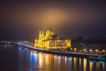 Fototapeta na wymiar A side view of the Hungarian Parliament building along the Danube River at night with the building lit up. Budapest