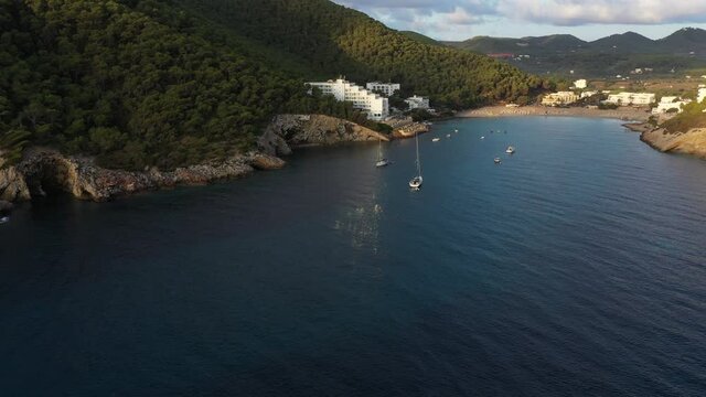 Flock of birds at sunset on a cliff. Aerial view of Cala Llonga beach. Beautiful aerial view of the bay at sunset. Ibiza, Spain.