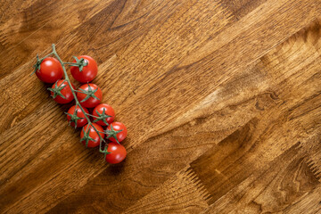 Background with red cherry tomatoes on the wooden table with copy space. Food concept for restaurant, cafe, delivery, spring, vegan, eco, raw.