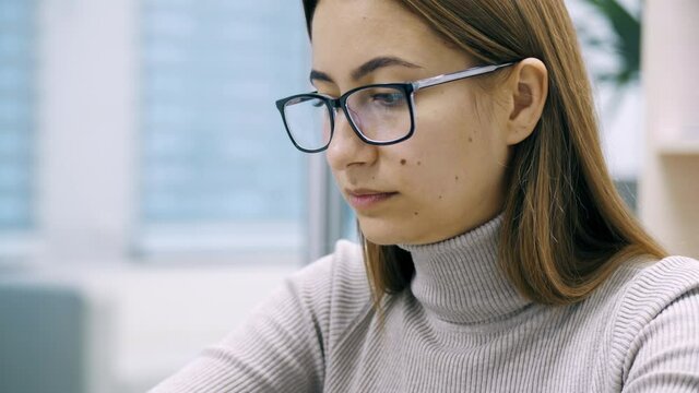 Beautiful woman, office worker in glasses using laptop at office. Female freelance, manager