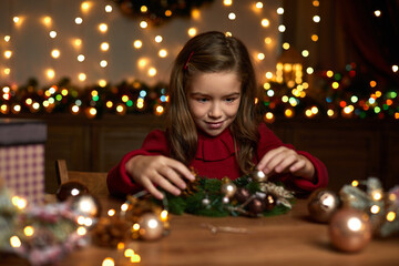 Obraz na płótnie Canvas happy cute little child girl makes a handmade Christmas wreath at home.