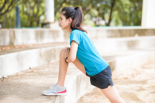A happy young woman in sportswear is exercising in park