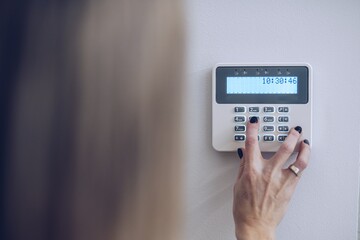 Security home system. Woman entering secret code on home alarm